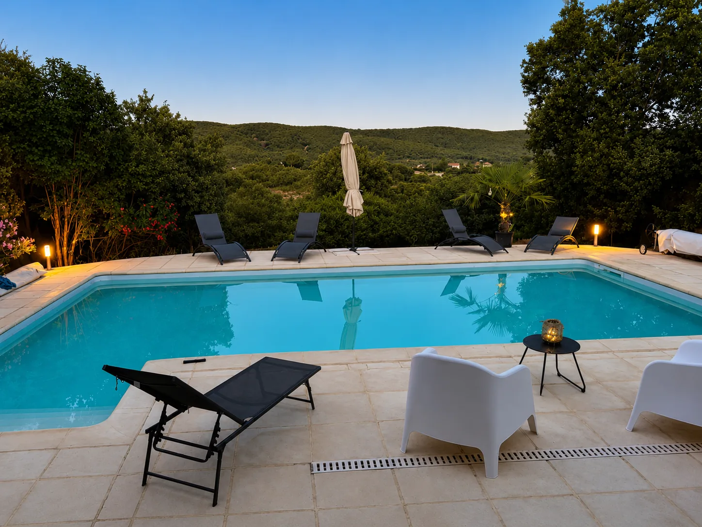 Piscine privée et terrasse du Mas de ValerYann au crépuscule, avec vue sur les collines ardéchoises